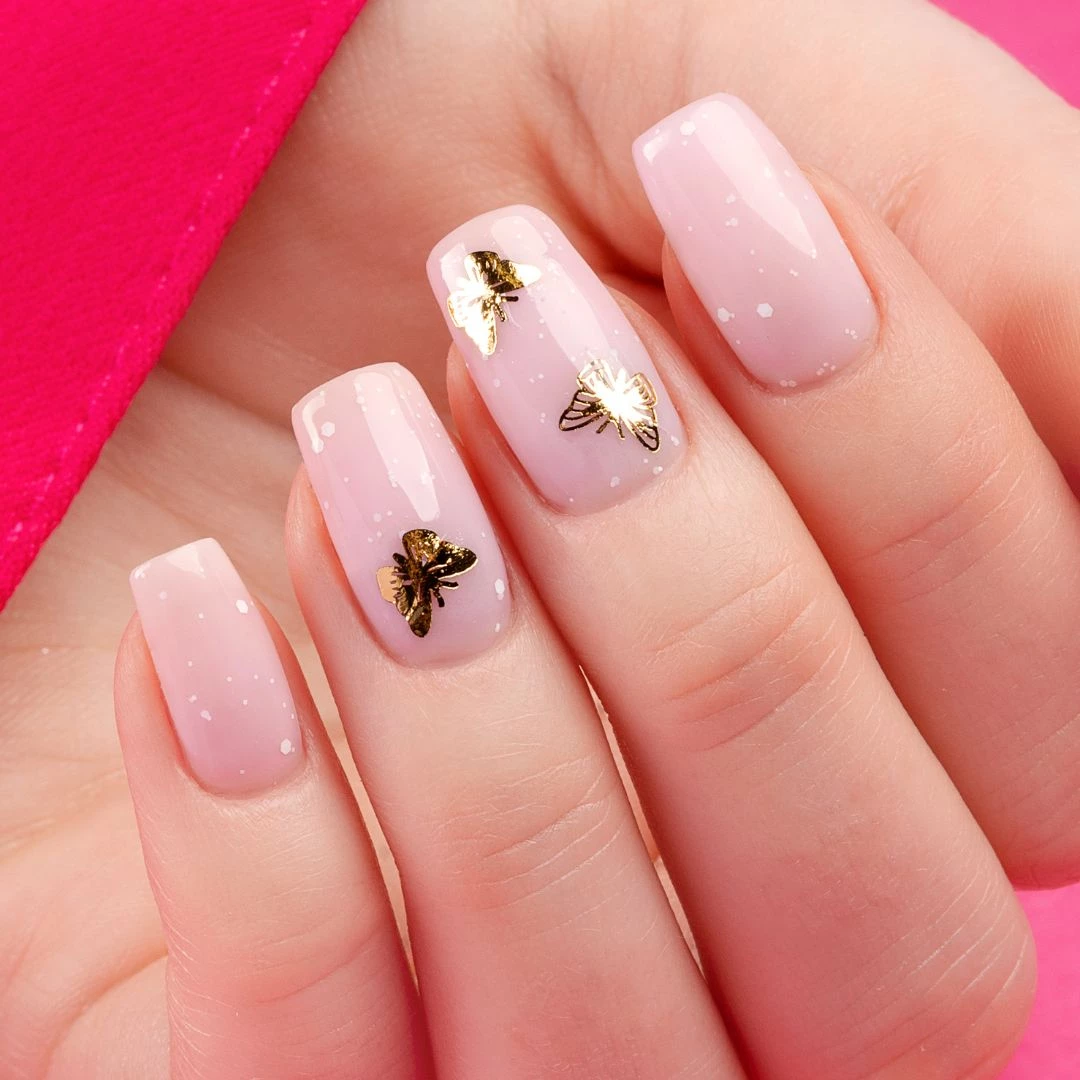 Różowa stylizacja paznokci ze złotymi naklejkami motylami
